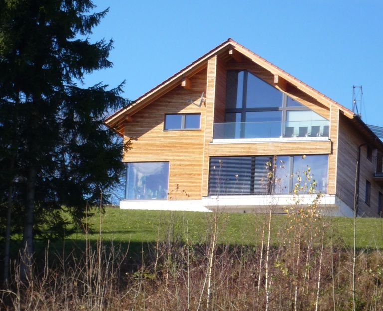 Das Massivholzhaus HausInNatura von Osten mit großer Fensterfront und Balkon