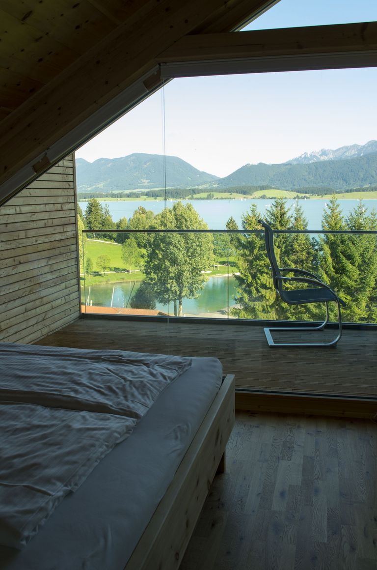 Schlafzimmer der Wohnung InZirbe mit Doppelbett und bodentiefem Fenster zum Forggensee